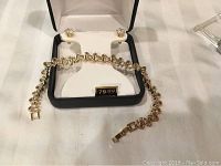 Bracelet and stud earrings displayed in a black and white jewelry box with price tag visible.