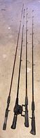 Photo showing four fishing rods laid on floor with visible grips and some rod details.