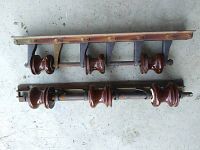 Photo showing two distinct antique electrical pole insulator assemblies placed on a concrete floor.