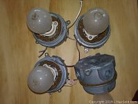 Four vintage lamp holders with three incandescent bulbs installed, metal and wiring visible, showing wear and rust.