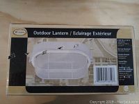 Photo of the original packaging box for the outdoor lantern, showing label details including dimensions, finish, and features.