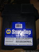 Photo of a black NAPA SnapTop Marine Group 24 battery box with label detailing compatibility and marine use.