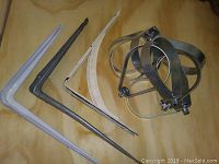 Photo of assorted brackets and hangers including three L-shaped brackets (plastic and metal) and three large metal band clamps.