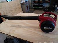 Side view of Homelite Vac Attack II leaf blower with tube attachment on wooden surface