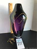 Front view of signed art glass vase with frog figurine beside it and a ruler for size reference.