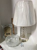 Overall view of the Seiko glass clock, crystal lamp with white pleated shade, and round cut glass dish.