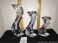 Three clear glass candlestick holders of varying heights in front of ruler for scale.