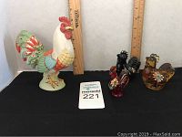 Lenox Morning Radiance rooster figurine and three smaller Fenton hand-painted glass rooster figurines displayed together with rulers showing scale.