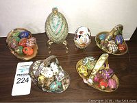 Overview of four seasonal egg baskets and two large decorative eggs on stands shown on table