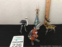 Four Russian blown glass figurines including an ostrich, rabbit, reindeer, and decorative piece with a ruler for scale.