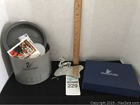 Crystal reindeer figurine with ruler showing size, Swarovski box, and cleaning kit container with instruction booklet inside.