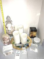 Overview of candles, shells in glass jars, acrylic cubes and remote control on golden decorative plate