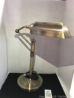 Full view of the brass tone table lamp showing adjustable arm and round base