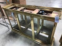 Front and top view of large rectangular glass display case with gold brass trim and glass sliding doors.