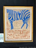 Frontal view of the framed artwork showing a blue zebra with accompanying red-brown handwritten text, framed in a bamboo-style wooden frame.