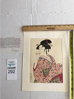 Full view of Japanese wood block print on mat board with rulers indicating size, and historical information sheet beside it.
