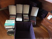 Photo showing ten purple containers holding assorted CDs, stacked weekly planners including Christian Carter planner, and an empty purple folding container.