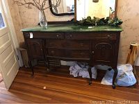 Frontal view of the wooden buffet showing dark wood construction, ornate carved details, two drawers and cabinet doors, with green marble-painted top.