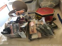 Wide view showing assorted unopened beauty products including makeup, brushes, and lipsticks in containers and boxes.