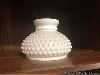 White hobnail glass lid with knob handle on wooden shelf