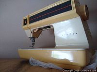 Close-up of Singer Model 621 B sewing machine showing cream and gold design with black and red stripe details.