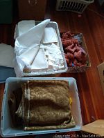 Three boxes containing fabrics and textiles including upholstery fabric, a christening gown, and yarn.