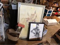 Wide view of the two framed art pieces, basket, and small wooden house decor