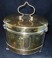 Front view showing the brass body with perforated side panels and the unique shaped handle on the lid.