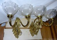 Pair of large brass wall sconces with two arms each, mounted upside down showing ribbed glass shades and detailed brass scrollwork.