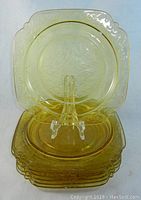 Stack of eight amber Madrid pattern dinner plates, showing color and shape with one plate on stand.