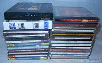Photo showing a collection of about 30 CDs stacked in two piles, with visible titles including B.B. King double CD, Andrea Bocelli, Verdi Greatest Hits, and others.