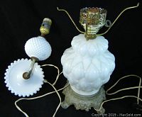 Full view of the set showing the milk glass table lamp with textured rounded pattern and matching wall sconce lying down, both with electric wiring and metal hardware.