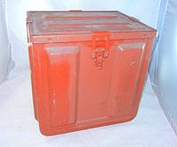 Front angle view of the large steel ammunition box showing red-orange color and latch.