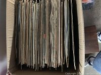 Top-down view of cardboard box filled with various rock vinyl LP records packed vertically