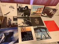 Collection of 11 Billy Joel vinyl record albums laid out, showing album covers including Cold Spring Harbor, Kohlhept Promo, Souvenir, Streetlife Serenade, 52nd Street, The Stranger, Piano Man, The Bridge, The Nylon Curtain, Glass Houses, and Greatest Hits Volumes 1 & 2.