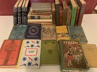 Photo showing a collection of approximately 20 vintage hardcover books including titles like 'The Adventures of Tom Sawyer,' 'Treasure Island,' 'Heidi,' and 'Tom Merrie's Children.' Books have various colored covers and some wear.