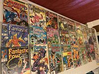 Photo showing 28 Fantastic Four comic books laid out on a wooden surface, various issues with different colorful covers visible.