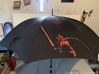 Black umbrella showing Darth Vader with red lightsaber graphic and Star Wars logo on top