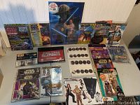 Photo showing an assortment of Star Wars collectibles including magazines, prints, catalogs, and posters arranged on a table.
