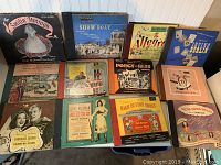 Photo showing 12 vintage 78 RPM Broadway record sets with original sleeves and boxes, featuring classic musicals and theatrical productions.