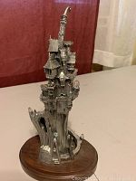 Full view of the Castle of Crystal Dreams sculpture showing its height, detailed castle features, and wooden base.