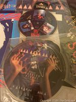 Photo showcasing two of the Thompson Twins picture records; one titled 'Doctor Doctor' with band member images on the vinyl disc and one 'Passion Planet' record with colorful artwork.