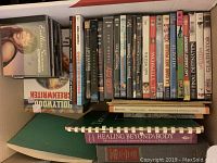 Top-down view showing DVDs lined up with titles visible, CDs stacked on left, and books below the DVDs and CDs