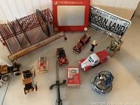 Wide shot of lot showing multiple wooden and metal vehicles, Etch A Sketch, license plate, figurines, letter opener, and record holder with records.