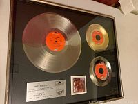 Framed display of three discs, plaque and photo lying flat on surface