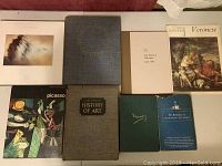 Overview of 8 art books arranged on a surface showing covers of each book with various art and text.