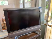 Full view of Sharp Aquos 32-inch LCD TV on silver stand with built-in speakers and logo details.