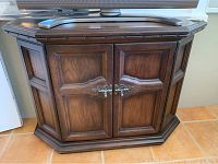 Front view of wood finish cabinet showing double doors and metal handles