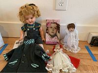Full view of all items in the lot: Shirley Temple doll, coat, two smaller dolls, and DVD