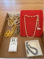 Overall tray view with red pouch, five jewelry pieces displayed